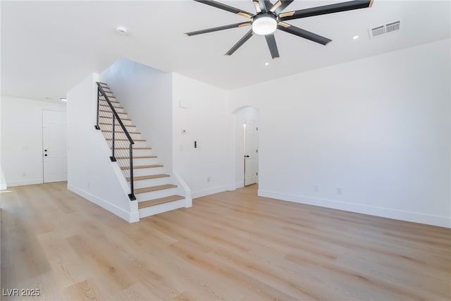 529 Fork Mesa Ct, Henderson, NV 89015 - unfurnished living room featuring arched walkways, ceiling fan, stairs, light wood-style floors, and baseboards