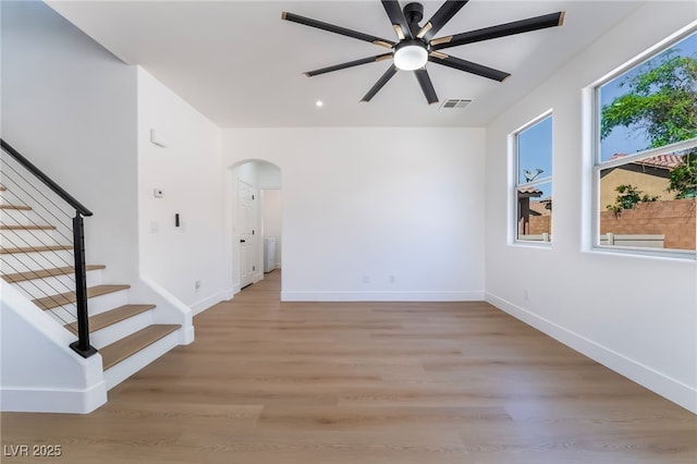 529 Fork Mesa Ct, Henderson, NV 89015 - empty room featuring arched walkways, ceiling fan, stairs, baseboards, and light wood-style flooring