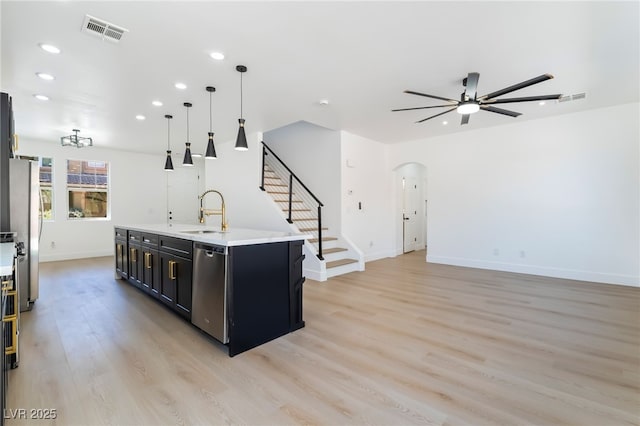 529 Fork Mesa Ct, Henderson, NV 89015 - kitchen with dark cabinets, a sink, arched walkways, ceiling fan, and light wood-type flooring