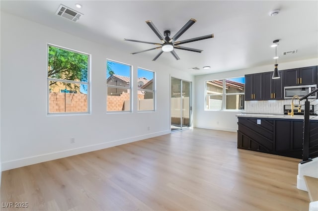 529 Fork Mesa Ct, Henderson, NV 89015 - kitchen with stainless steel microwave, dark cabinetry, ceiling fan, and light wood-style flooring