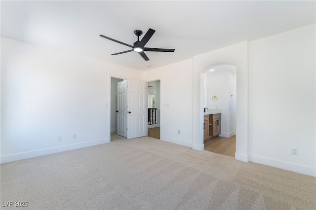529 Fork Mesa Ct, Henderson, NV 89015 - unfurnished bedroom with arched walkways, light colored carpet, baseboards, ensuite bathroom, and a ceiling fan
