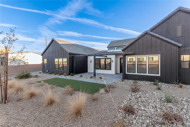 rear view of house featuring board and batten siding and fence