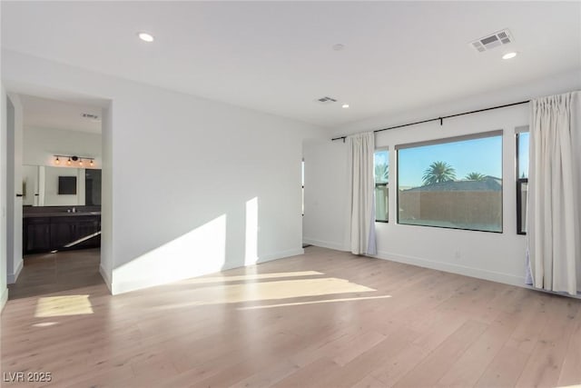 spare room with light wood-type flooring, baseboards, recessed lighting, and a sink