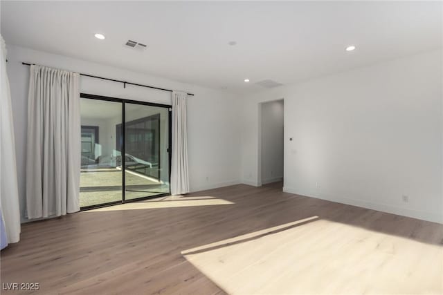 spare room with wood finished floors, baseboards, and recessed lighting
