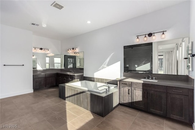 full bathroom featuring tile patterned floors, a bath, and two vanities
