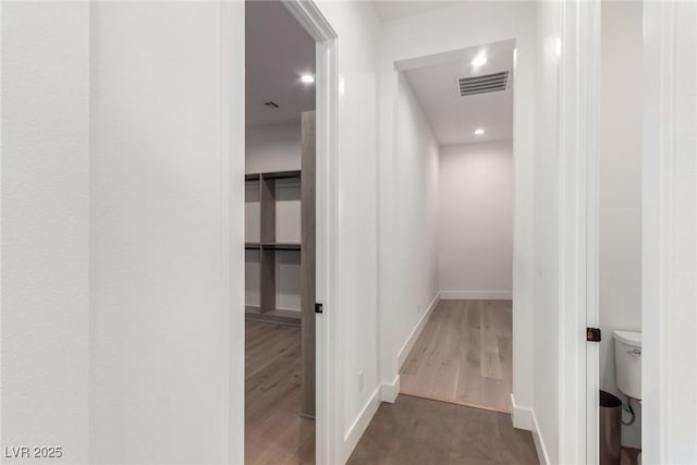 corridor featuring baseboards, wood finished floors, and recessed lighting
