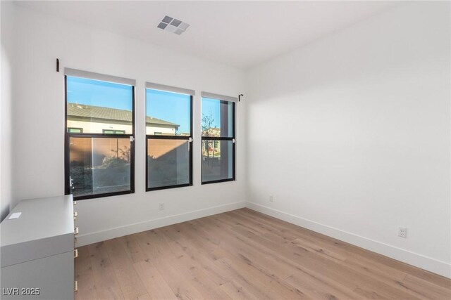 empty room featuring light wood finished floors and baseboards