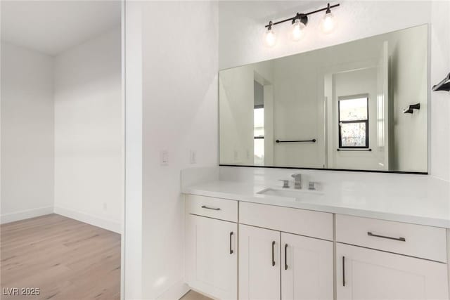 bathroom featuring wood finished floors, vanity, and baseboards
