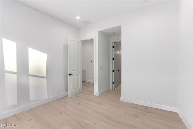 empty room with light wood-type flooring, baseboards, and recessed lighting