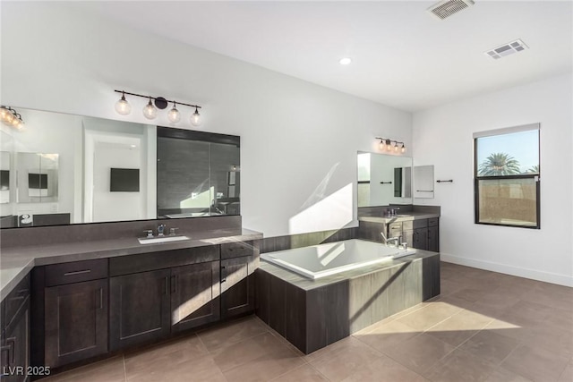 full bath featuring a bath, two vanities, and tile patterned floors