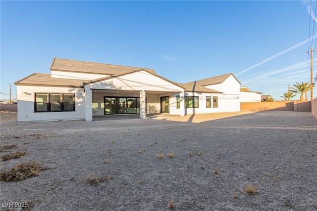 rear view of property with stucco siding, a patio area, and fence
