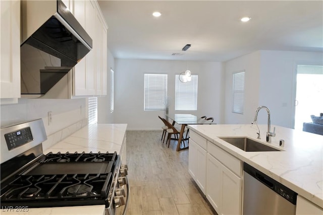 6250 Lamont Hills Ave, Las Vegas, NV 89139 - kitchen with appliances with stainless steel finishes, range hood, white cabinets, light wood-style floors, and light stone countertops