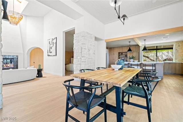 dining room featuring light wood-style floors, a towering ceiling, baseboards, and decorative columns