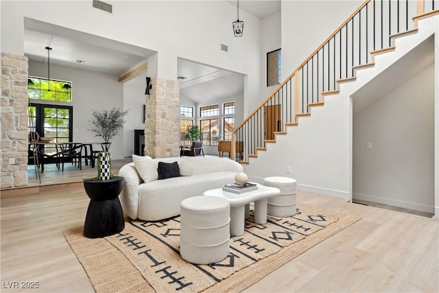 living room with plenty of natural light, wood finished floors, a towering ceiling, ornate columns, and baseboards