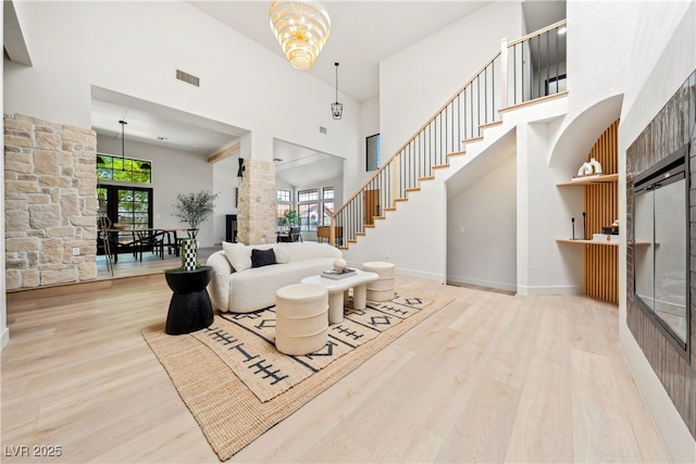living room with a towering ceiling, plenty of natural light, wood finished floors, baseboards, and stairs