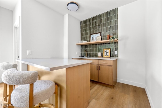 indoor bar featuring light wood-type flooring and baseboards