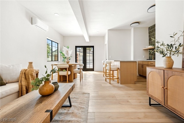living room with a wall mounted AC, beamed ceiling, light wood-type flooring, and bar