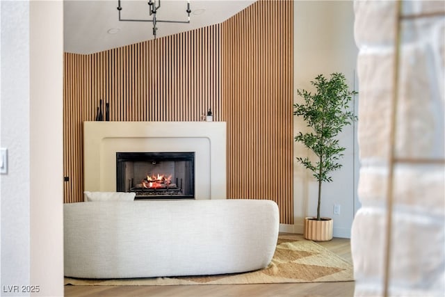 detailed view of a lit fireplace, wood finished floors, and a chandelier