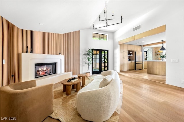 living room featuring light wood-style floors, a high ceiling, a glass covered fireplace, and healthy amount of natural light