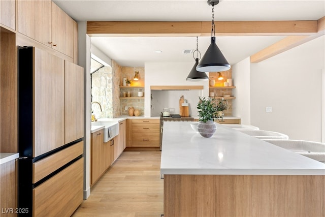 kitchen featuring open shelves, light brown cabinets, a sink, light countertops, and a kitchen island
