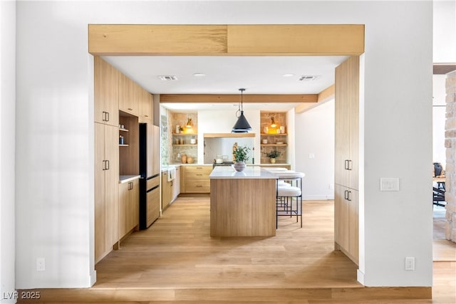 kitchen with light brown cabinets, fridge, modern cabinets, and a kitchen bar