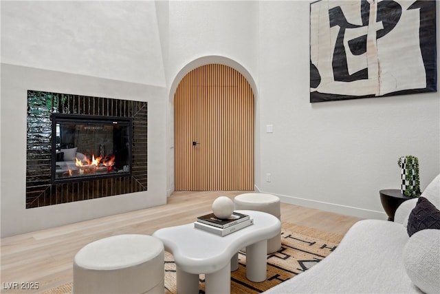 living room with wood finished floors, a glass covered fireplace, and baseboards