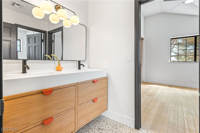 full bathroom with baseboards, double vanity, ceiling fan, vaulted ceiling, and speckle patterned floor