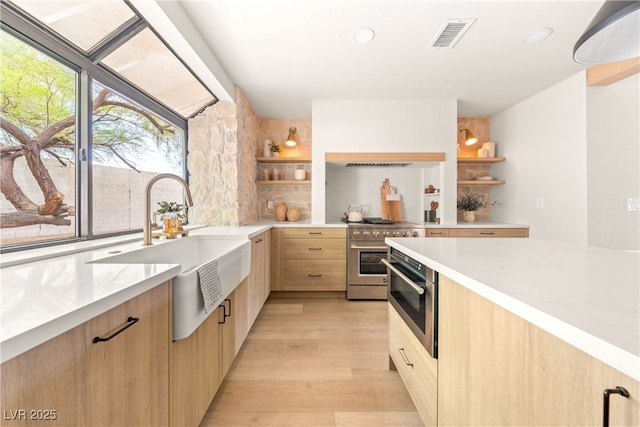 kitchen featuring open shelves, light brown cabinetry, a sink, stainless steel appliances, and recessed lighting