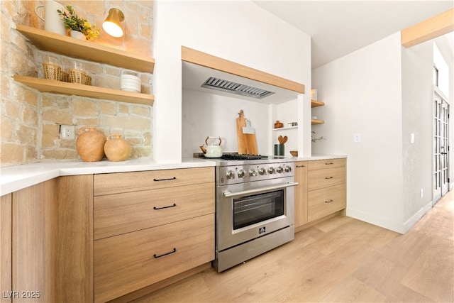 kitchen with high end stainless steel range oven, open shelves, light brown cabinets, light wood-style flooring, and light countertops
