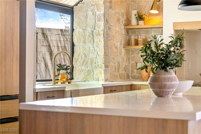 kitchen view of a sink, tasteful backsplash, brown cabinetry, and modern cabinets