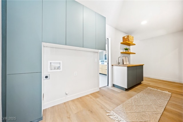 washroom with hookup for an electric dryer, hookup for a washing machine, light wood-type flooring, cabinet space, and baseboards