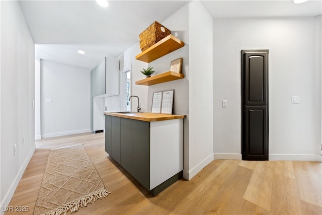 kitchen featuring butcher block counters, a sink, open shelves, light wood-style flooring, and recessed lighting
