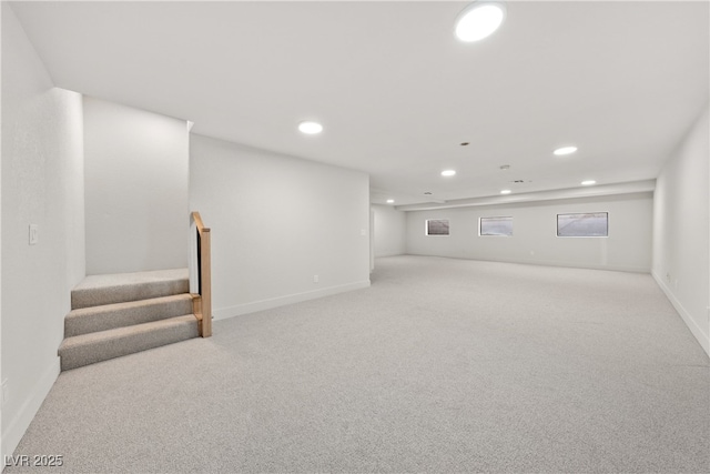 basement with recessed lighting, light colored carpet, stairs, and baseboards