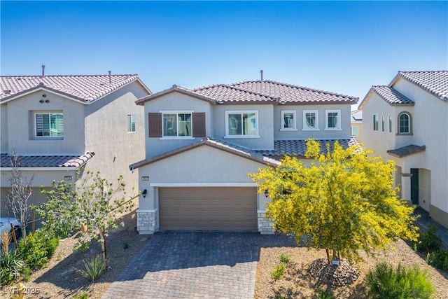 mediterranean / spanish house with a tile roof, stucco siding, and decorative driveway