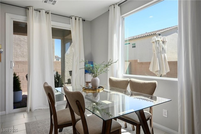 tiled dining room featuring decorative columns and baseboards