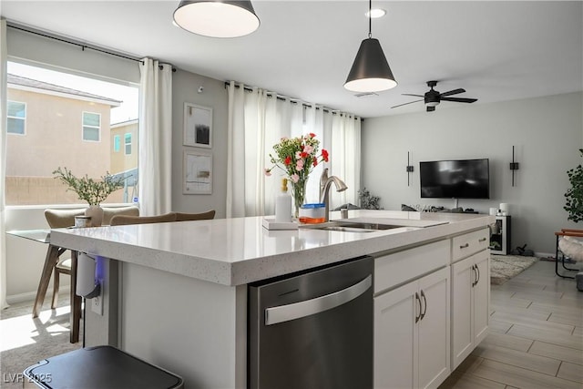 kitchen with dishwasher, open floor plan, a ceiling fan, white cabinets, and a sink