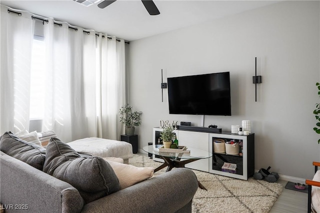living room with a ceiling fan and baseboards