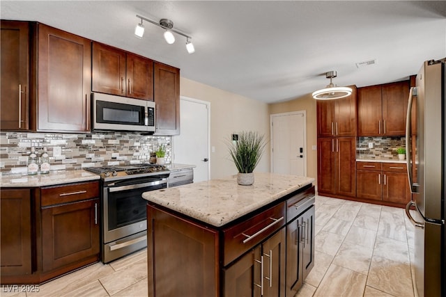 6117 Foxcroft Ave, Las Vegas, NV 89108 - kitchen featuring stainless steel appliances, tasteful backsplash, light stone counters, a kitchen island, and hanging light fixtures
