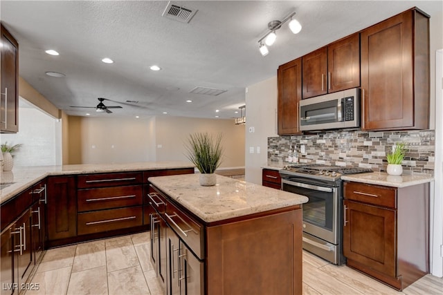 6117 Foxcroft Ave, Las Vegas, NV 89108 - kitchen with appliances with stainless steel finishes, ceiling fan, decorative backsplash, light stone counters, and a peninsula