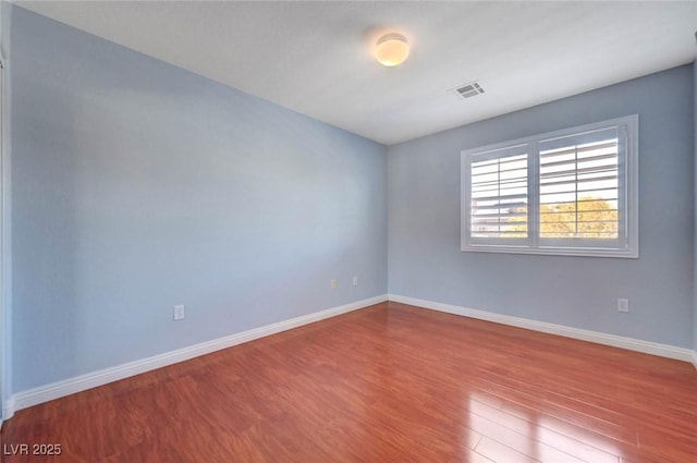 empty room featuring wood finished floors and baseboards