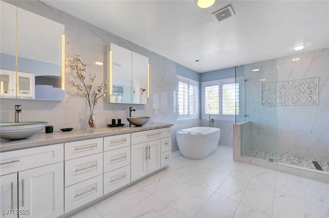 bathroom featuring marble look tiles, a marble finish shower, a soaking tub, and double vanity