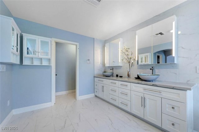 bathroom with marble finish floors, baseboards, and double vanity