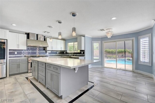 kitchen featuring gray cabinets, wall chimney range hood, high end stainless steel range, fridge, and light countertops