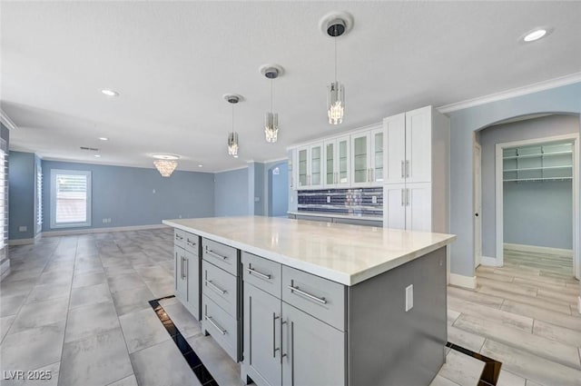 kitchen with baseboards, gray cabinets, white cabinets, a center island, and hanging light fixtures