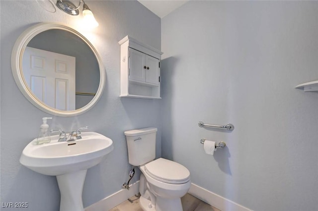 half bath featuring toilet and baseboards