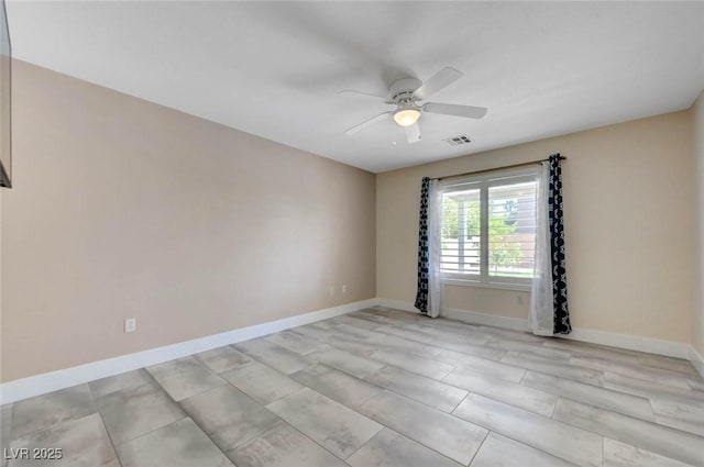 empty room featuring a ceiling fan and baseboards