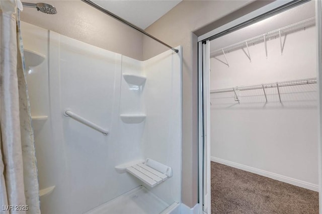 bathroom featuring a stall shower, a walk in closet, and baseboards