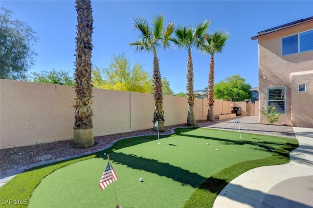 fenced backyard featuring an area to practice putting