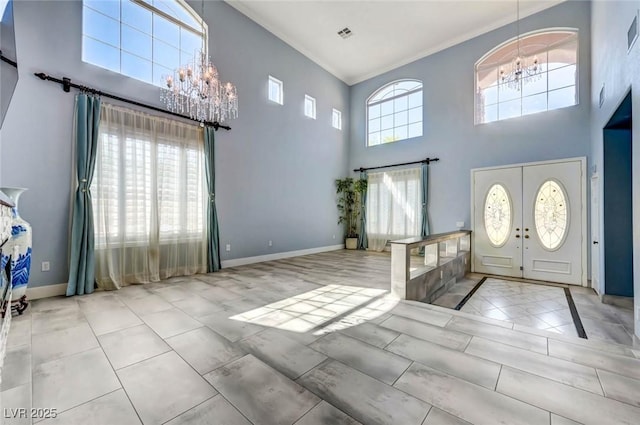 foyer entrance featuring a chandelier, a high ceiling, crown molding, and baseboards