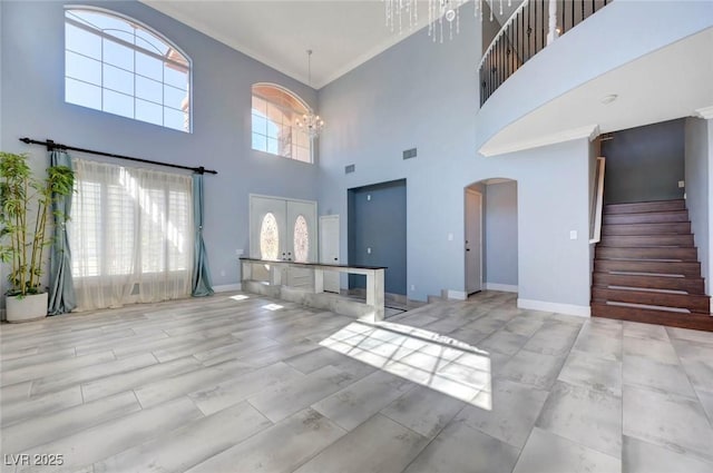 unfurnished living room with arched walkways, a towering ceiling, stairway, baseboards, and a chandelier